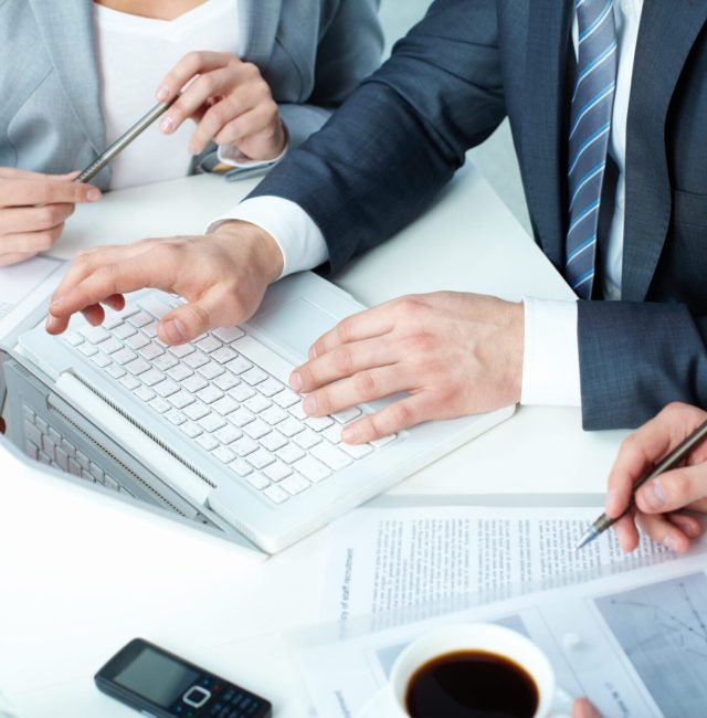 Pointing at display Group of business people working with laptop at meeting